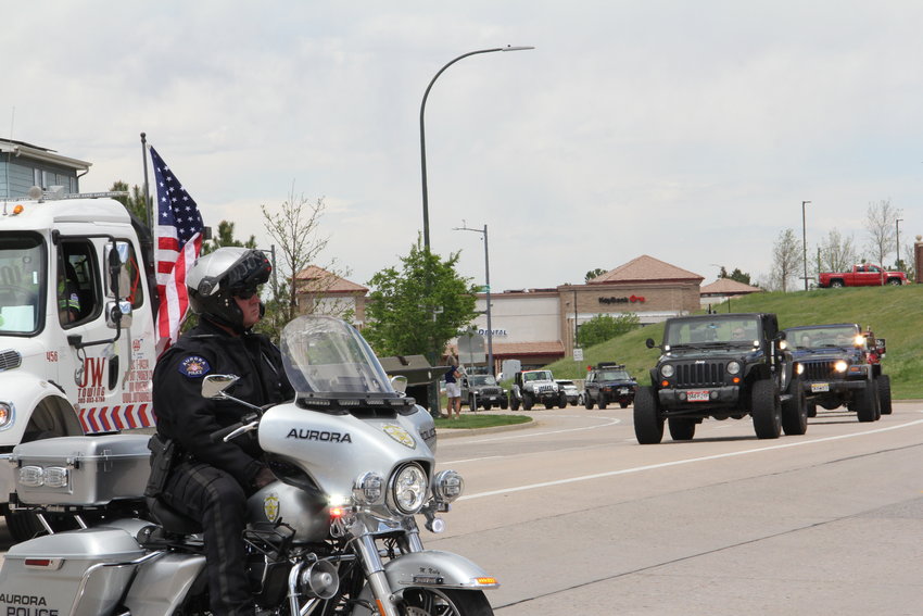 An Aurora police officer sits to keep traffic stopped as a motorcade of more than 200 Jeeps drove by for a May 15 memorial service for Kendrick Castillo.